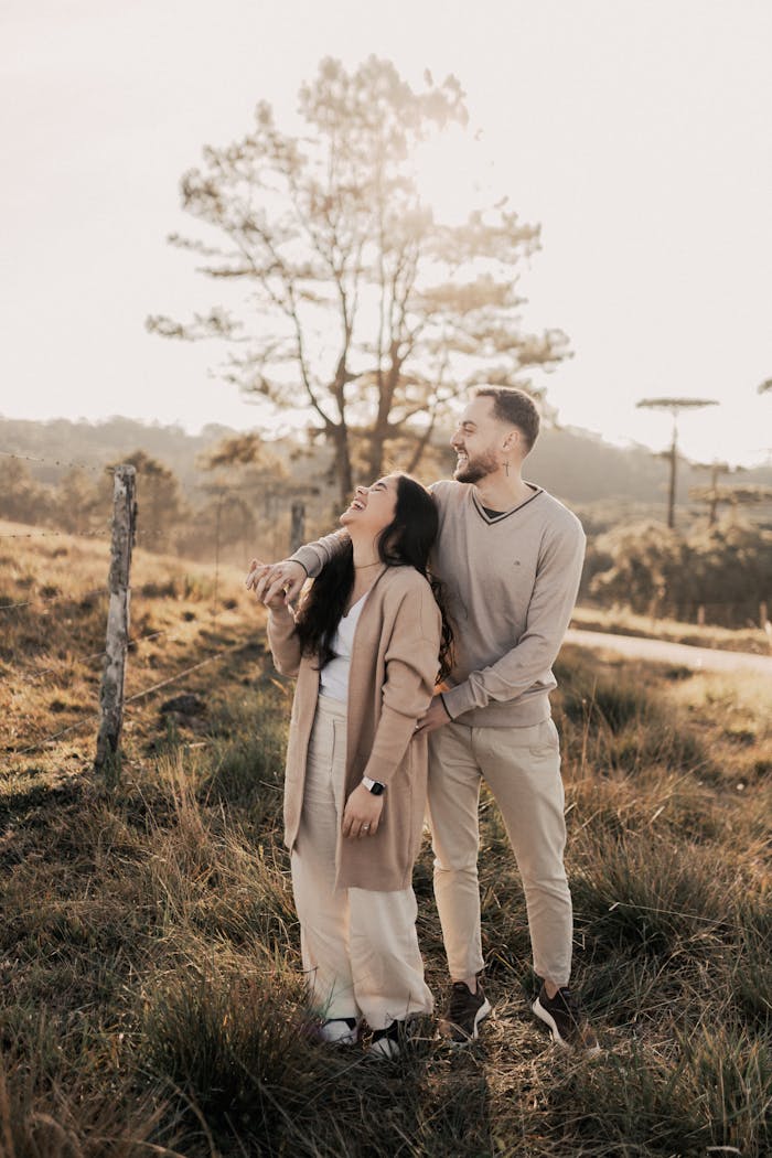 gallery-5 A joyful couple standing in a sunlit rural field, enjoying a moment together.